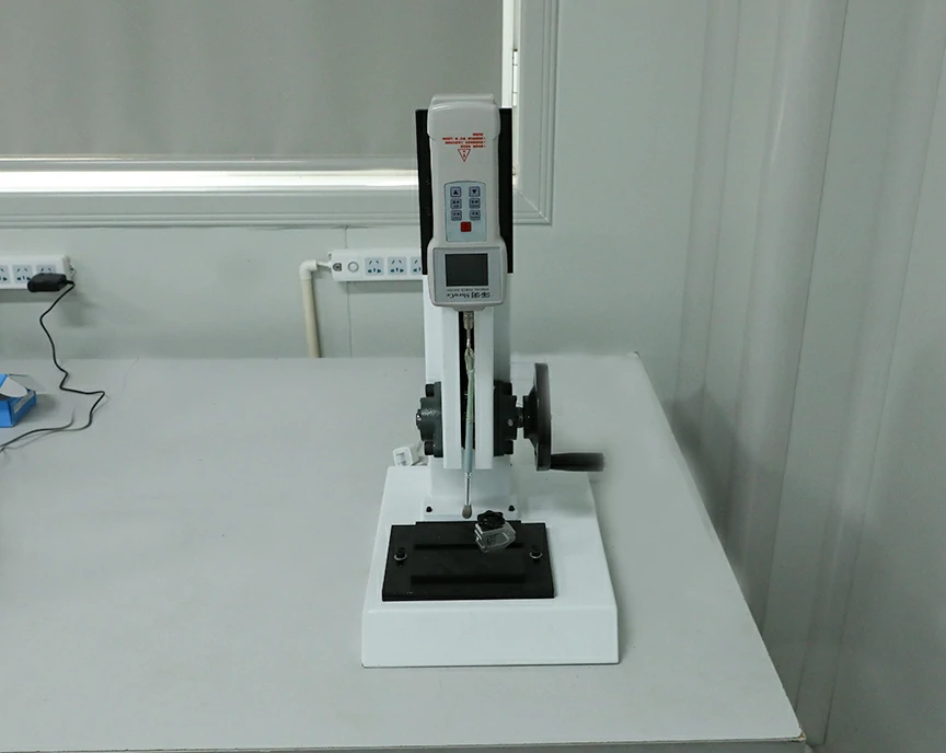 Tensile tester for evaluating adhesive bond strength in brush manufacturing.
