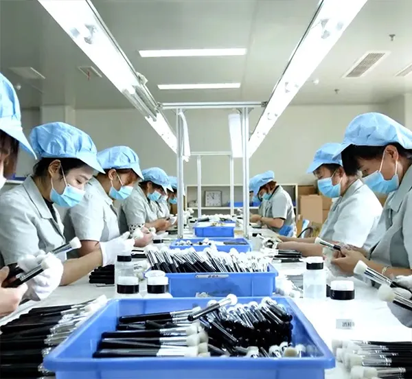 Factory workers assembling makeup brushes on production line, illustrating mass production capabilities.