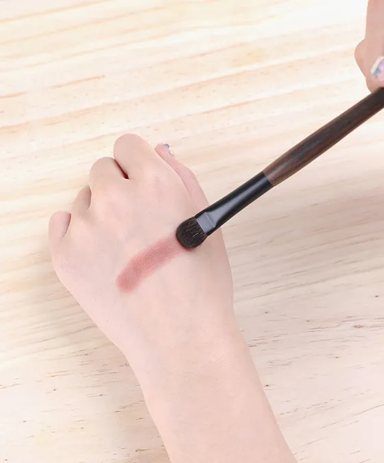 Y-s109 eyeshadow brush applying product on the back of the hand, showing color payoff