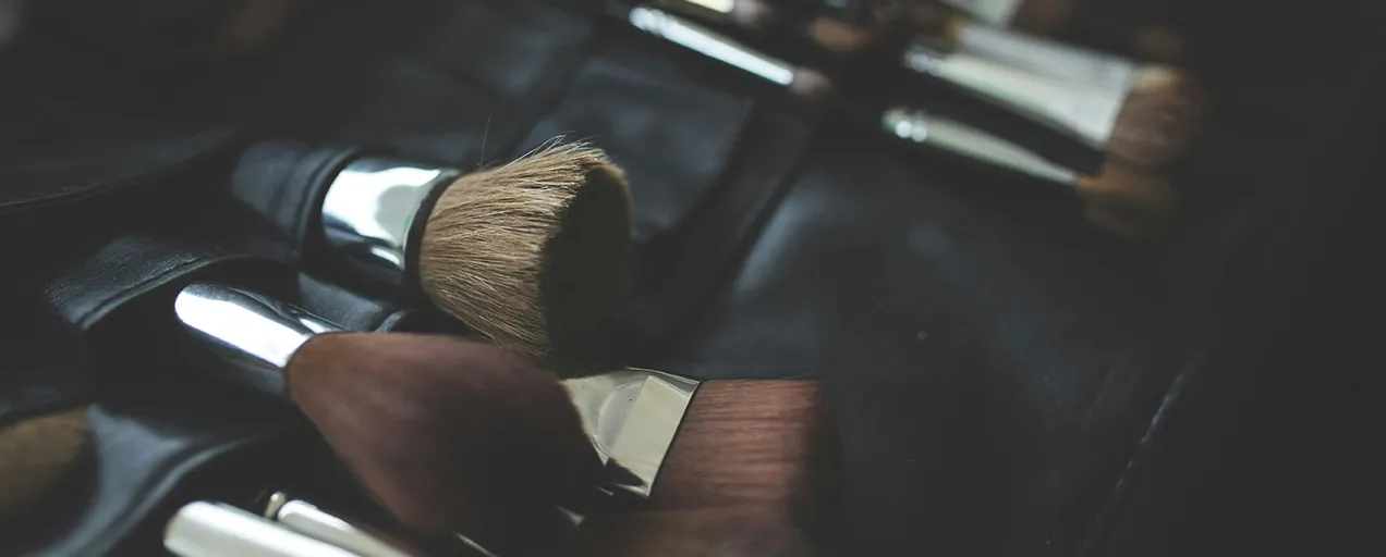A set of professional makeup brushes laid out on a black leather mat, showing different makeup brushes types and their uses.